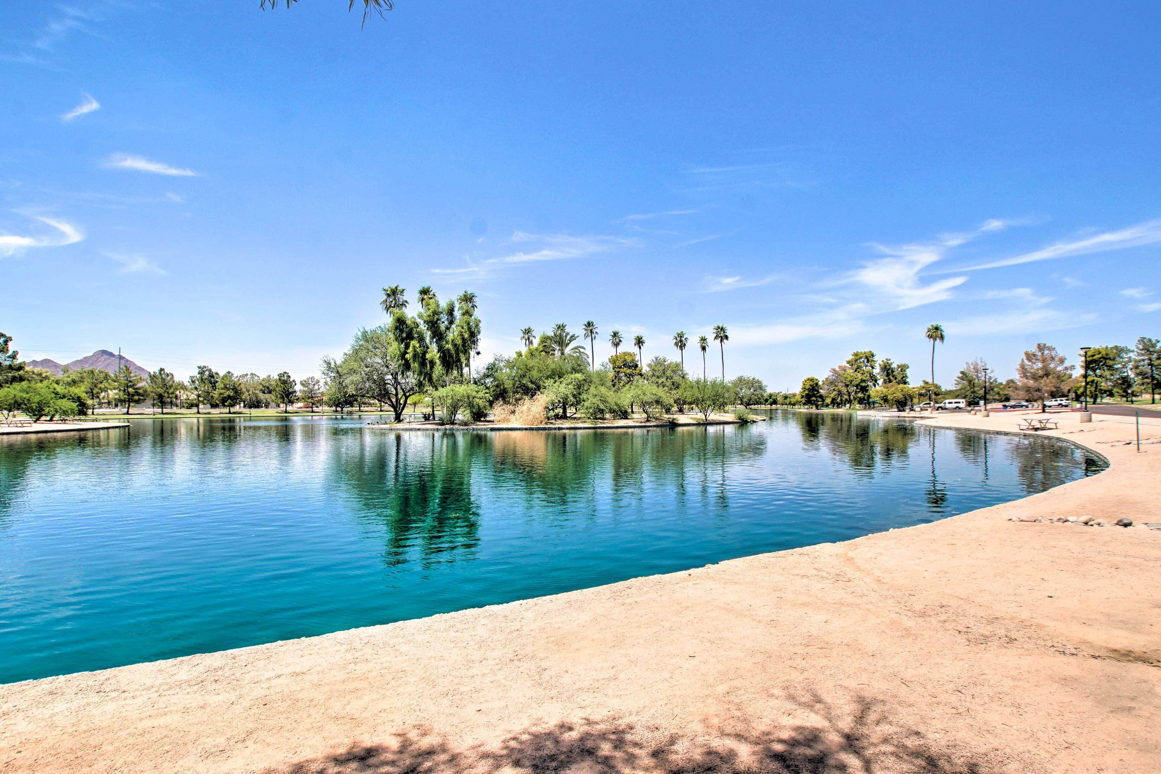 A clear blue sky, a calm lake, and a sandy shore with trees.