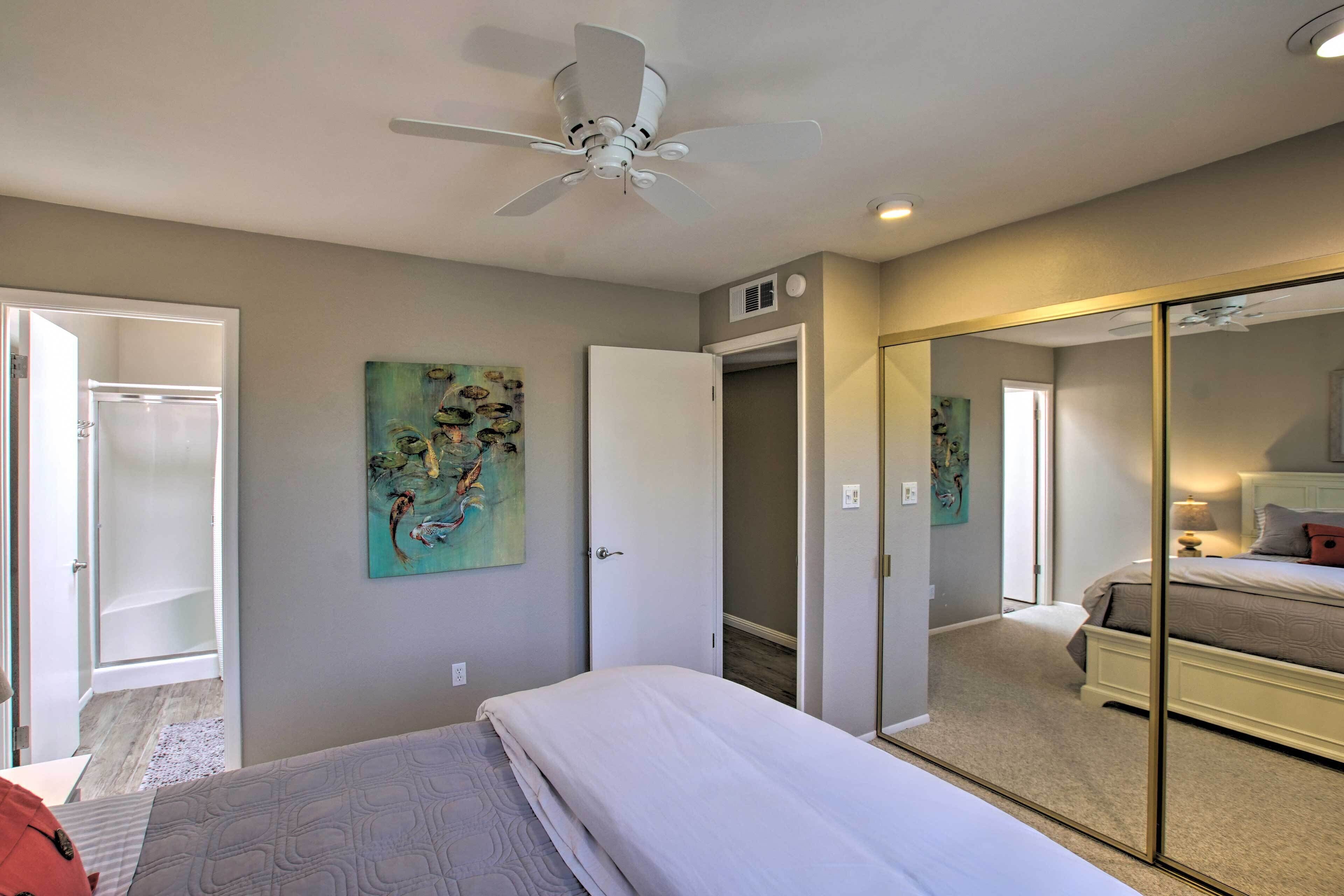 Une chambre à coucher avec un lit, un ventilateur de plafond, une porte et un miroir.