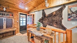A log cabin interior with wooden walls, a fur rug, a bench, and mounted animal heads. - Secluded Retreat w/ Wood Stove, 11 Mi to Bozeman! (Gallatin Gateway)