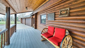 A log cabin with a wooden porch, a wooden bench with red cushions, and a framed fish picture on the wall. - Secluded Retreat w/ Wood Stove, 11 Mi to Bozeman! (Gallatin Gateway)