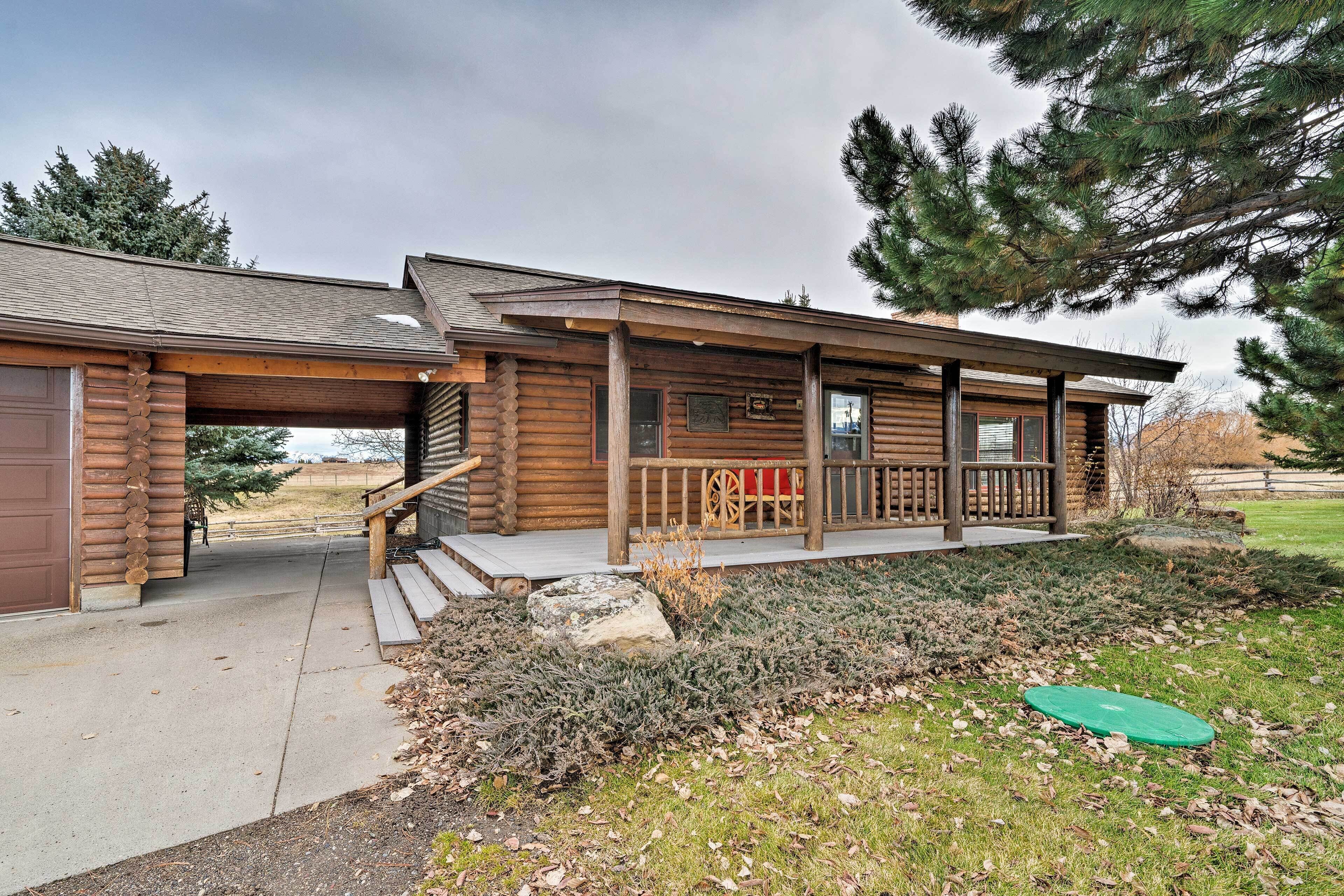 A log cabin with a porch, a garage, and a stone pathway leading to the entrance.