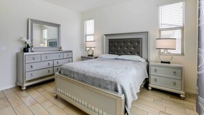Un dormitorio con cama, cómoda, mesitas de noche y espejo.