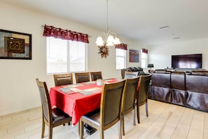 A dining area with a red tablecloth, wooden chairs, and a chandelier.