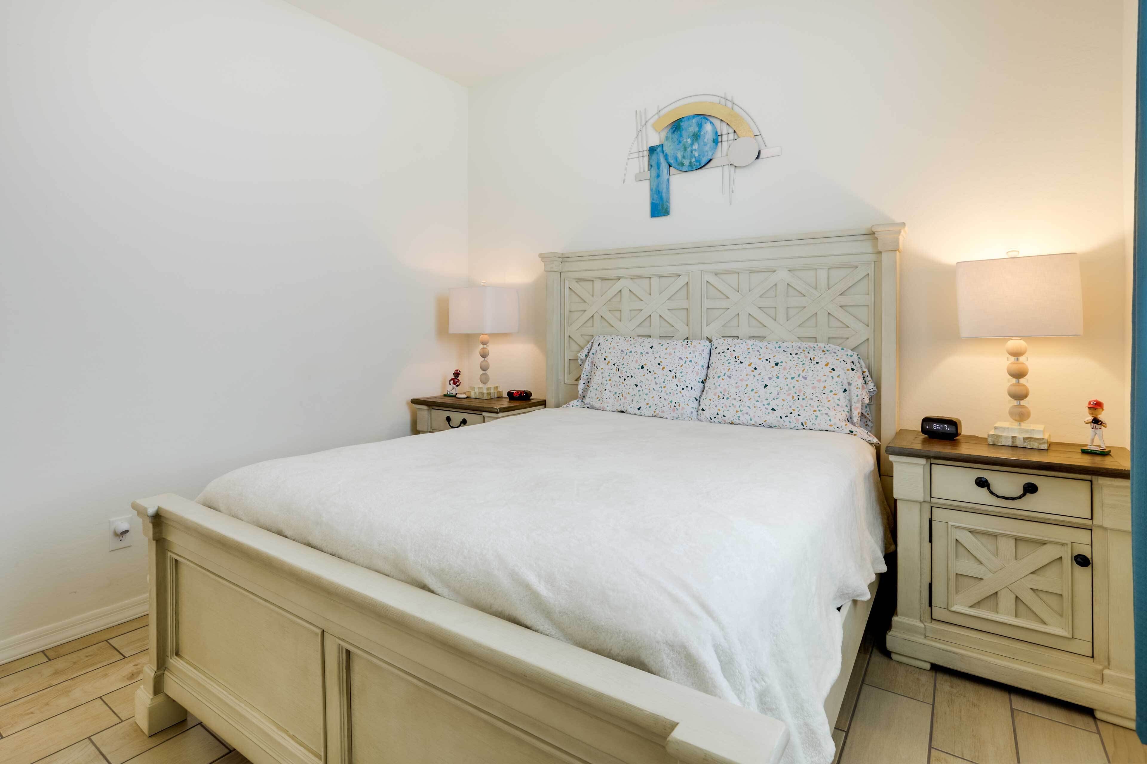A bedroom with a bed, nightstands, and a wall clock.