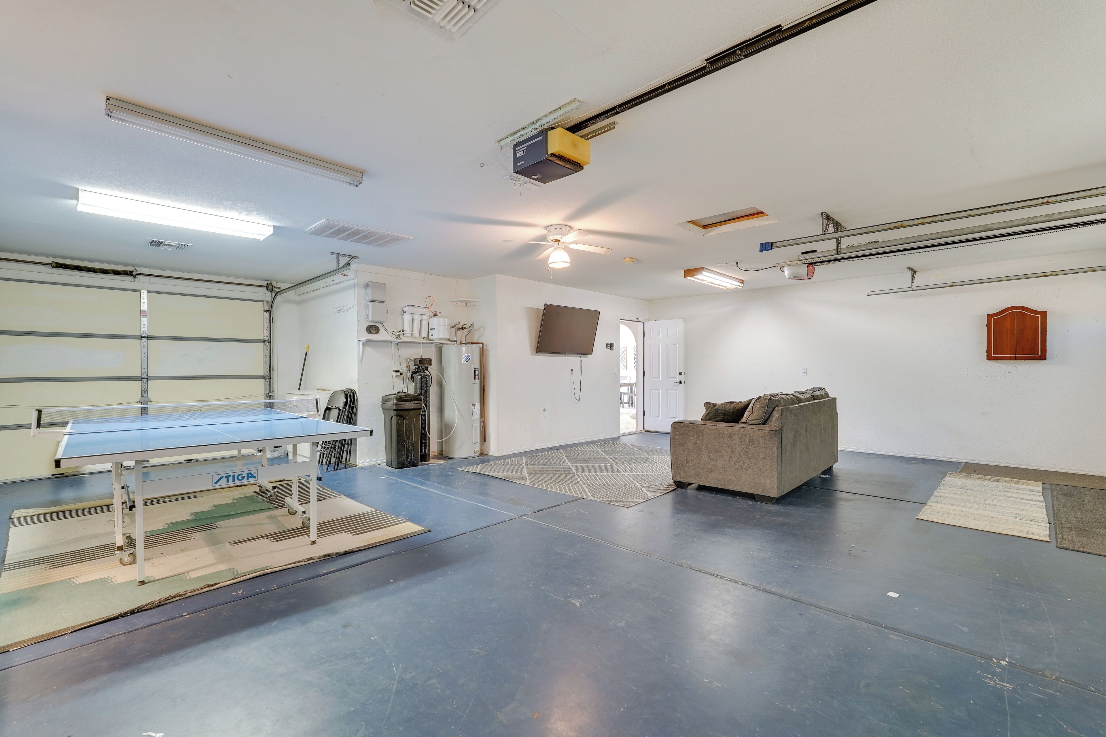 A spacious room with a ping pong table, a couch, and a door leading to another area.