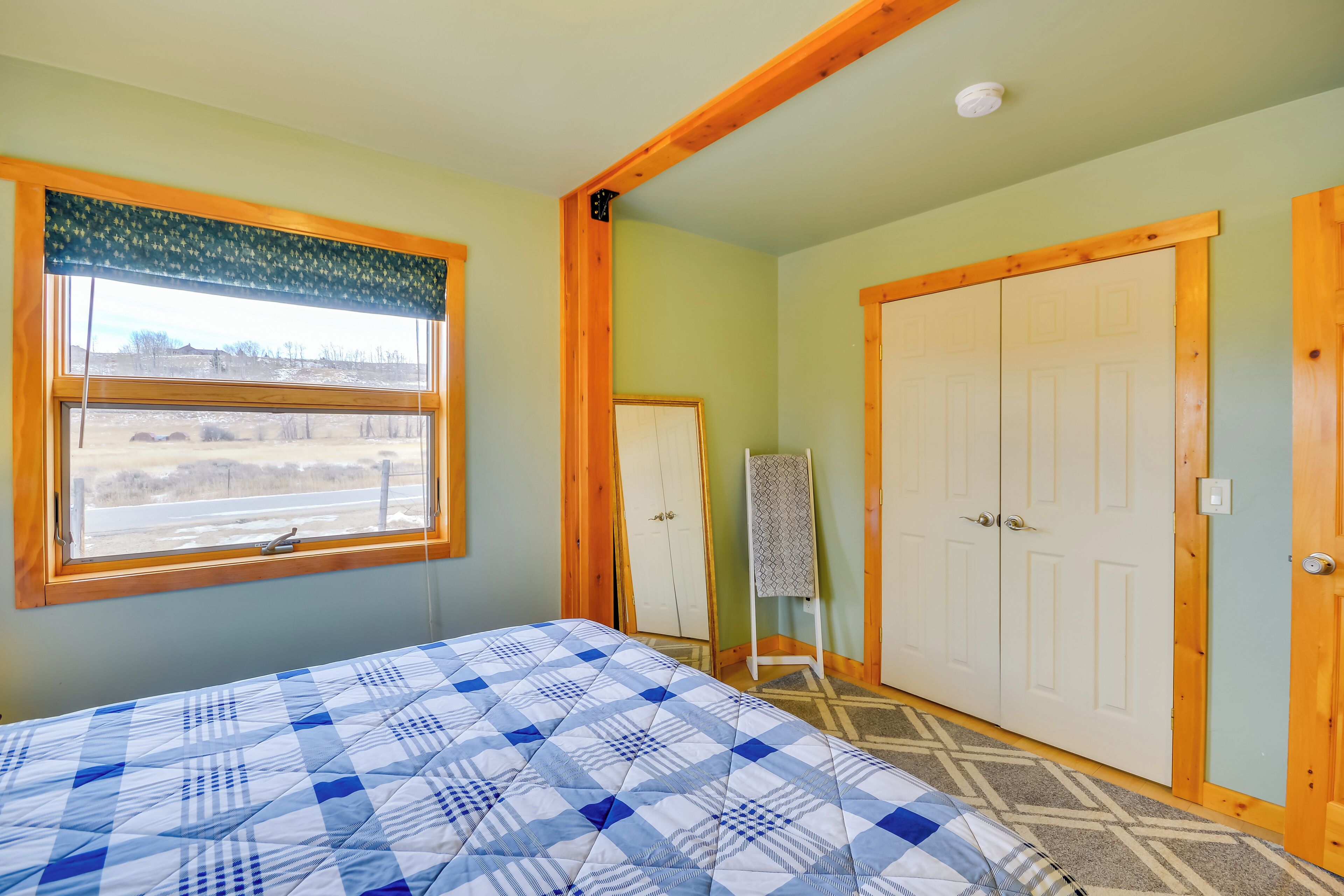 Un dormitorio con cama, ventana, armario y puerta.