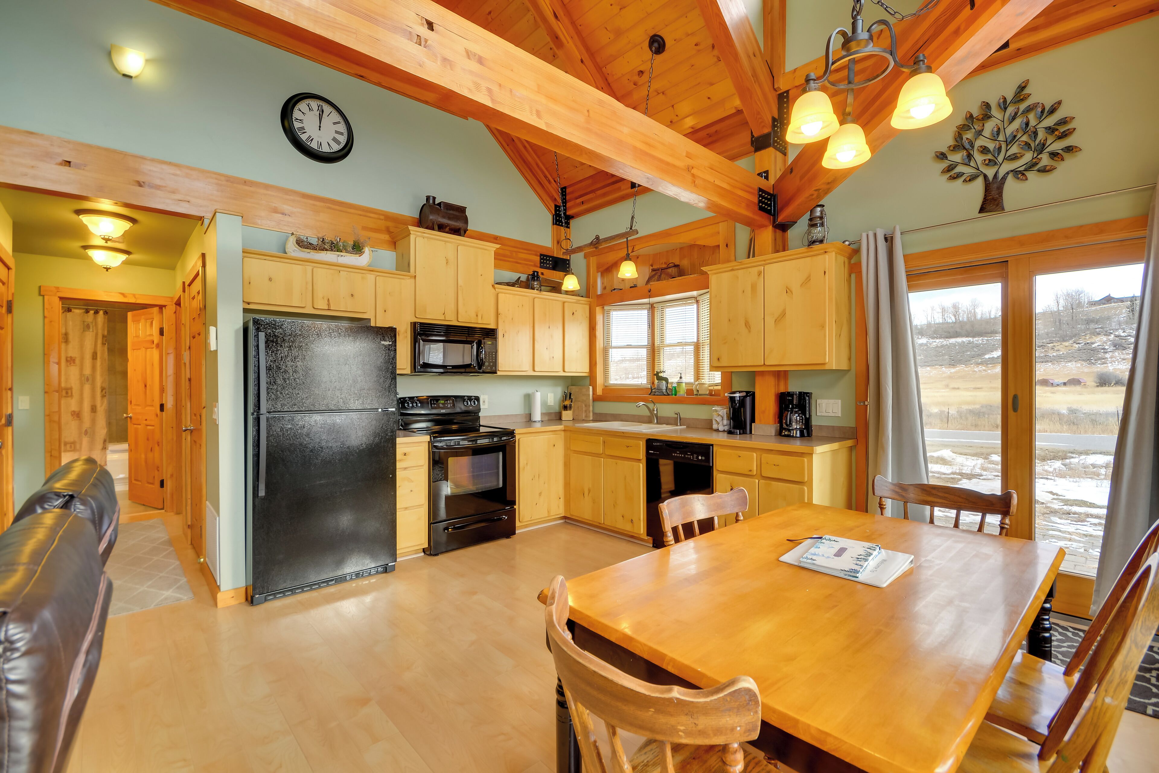 A cozy kitchen with wooden cabinets, a black refrigerator, and a dining area with a wooden table and chairs.