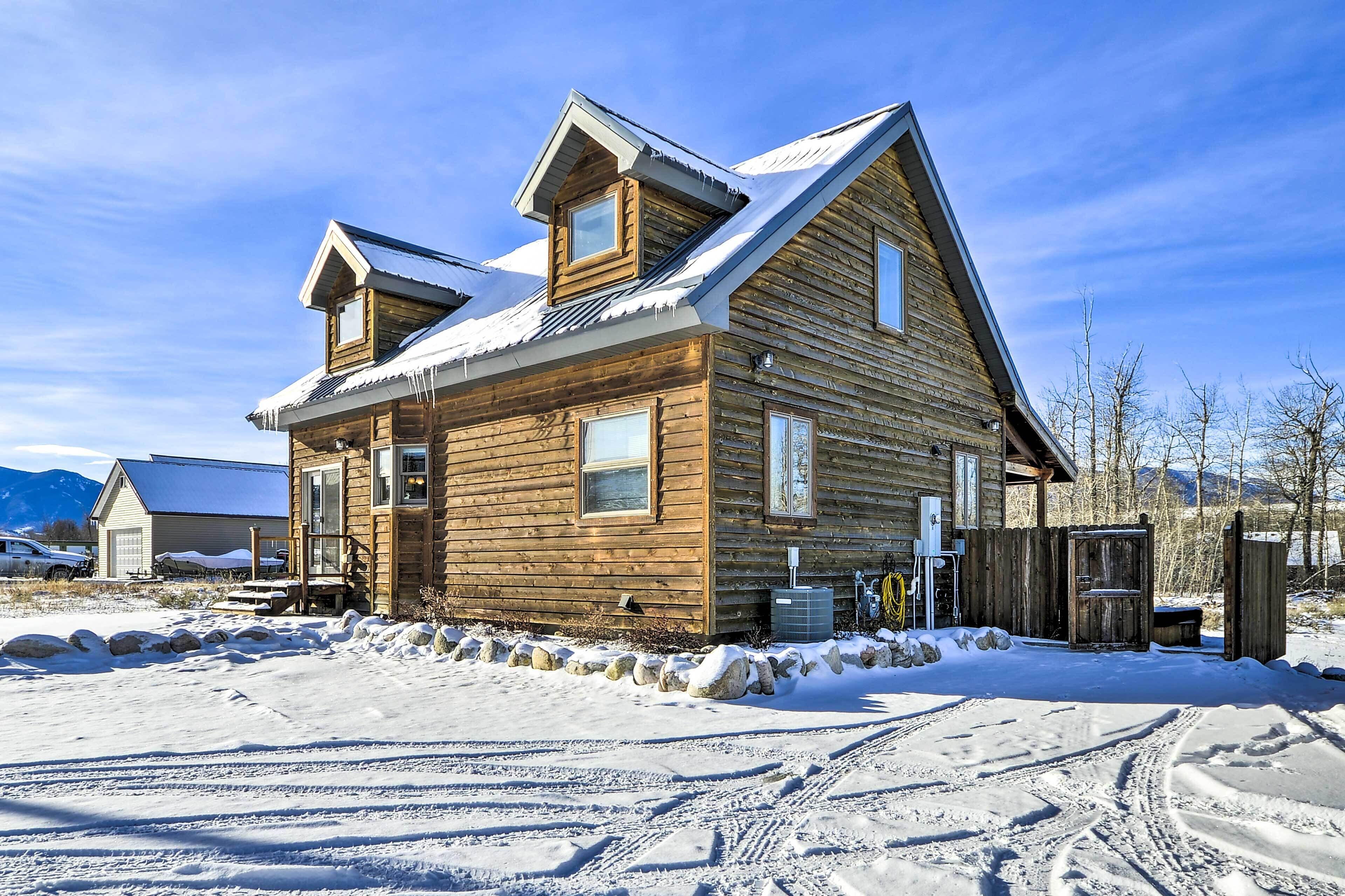 A wooden cabin with a sloped roof, a front porch, and a visible garage.
