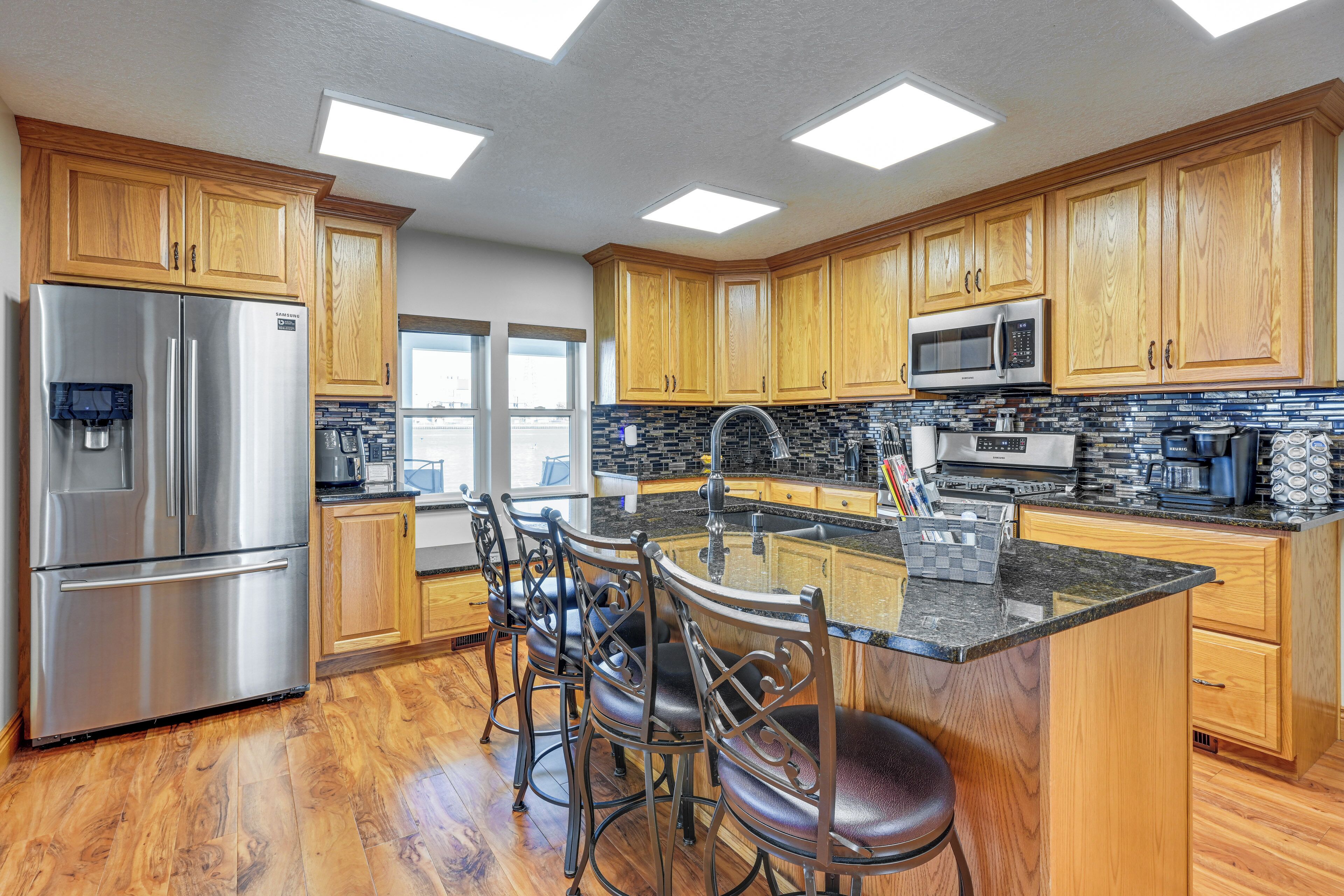 A modern kitchen with wooden cabinets, stainless steel appliances, and a central island with bar stools.