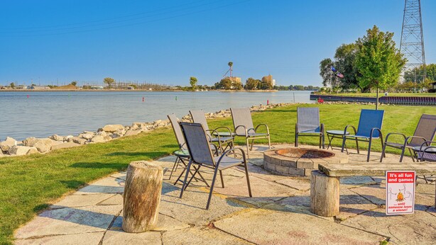 A lakeside patio with outdoor seating and a fire pit.