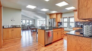 A spacious kitchen with wooden cabinets, a stainless steel refrigerator, and a large island with a sink.