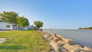 A lakeside property with a grassy lawn, a rocky shoreline, and a dock extending into the water.