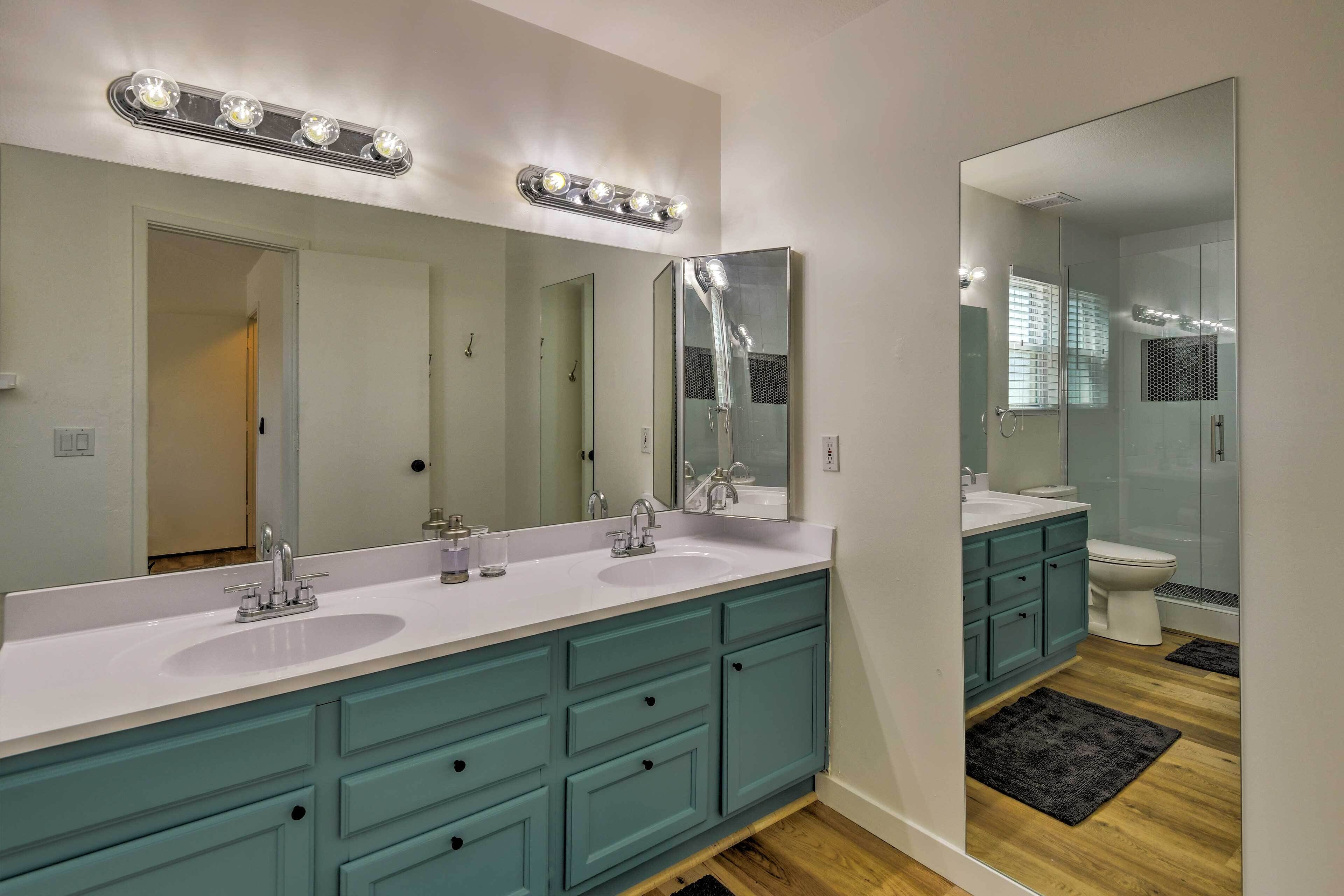 A modern bathroom with two sinks, a large mirror, and a shower.