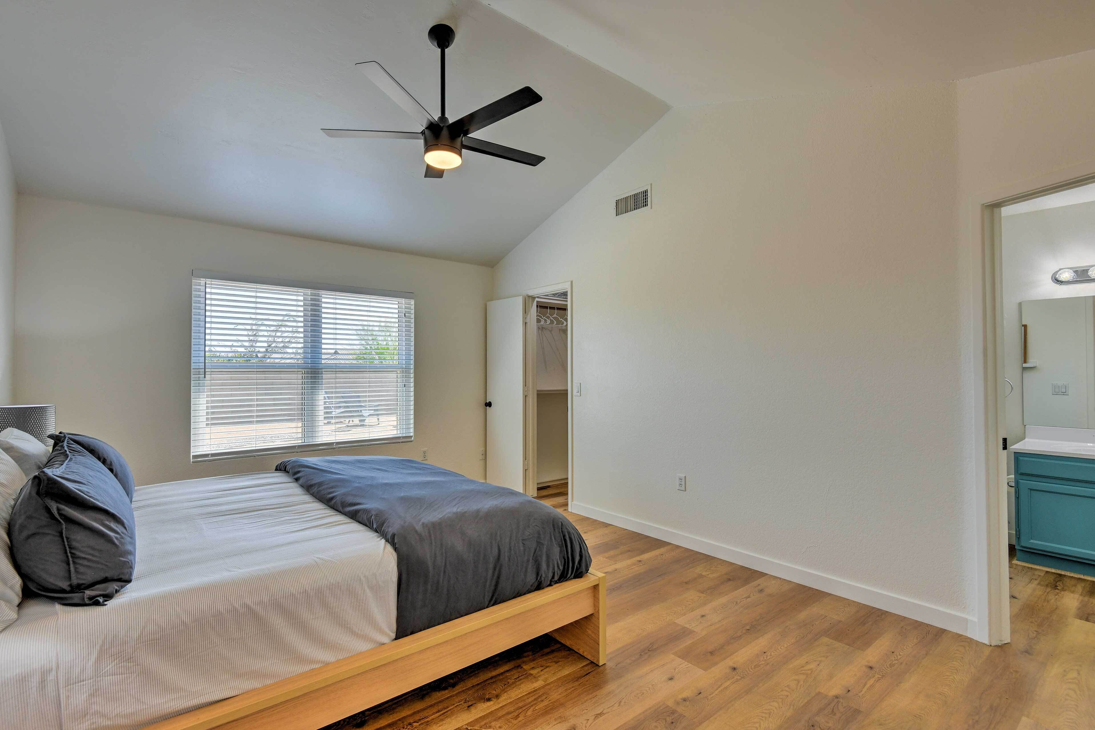 A bedroom with a bed, a ceiling fan, a window with blinds, and a wooden floor.