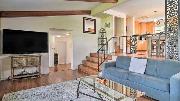 A living room with a flat-screen TV, a blue sofa, a glass coffee table, and a staircase leading to the upper floor. - Seminole Home: 1 Mi to Indian Shores Beach! (Seminole)