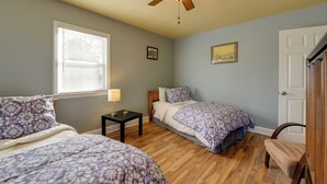 Un dormitorio con dos camas, ventilador de techo, ventana con persianas y una puerta.