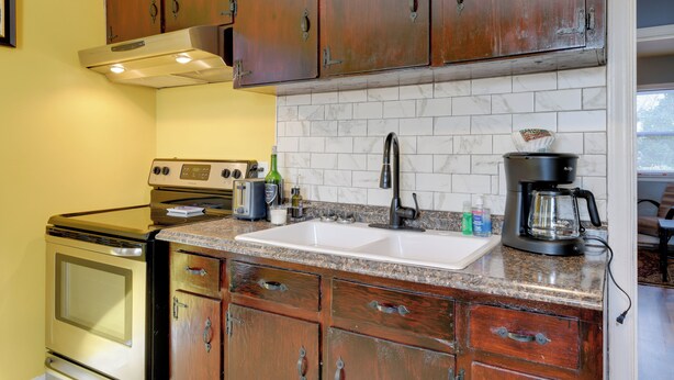 Una cocina con armarios de madera, un lavabo blanco y una estufa.