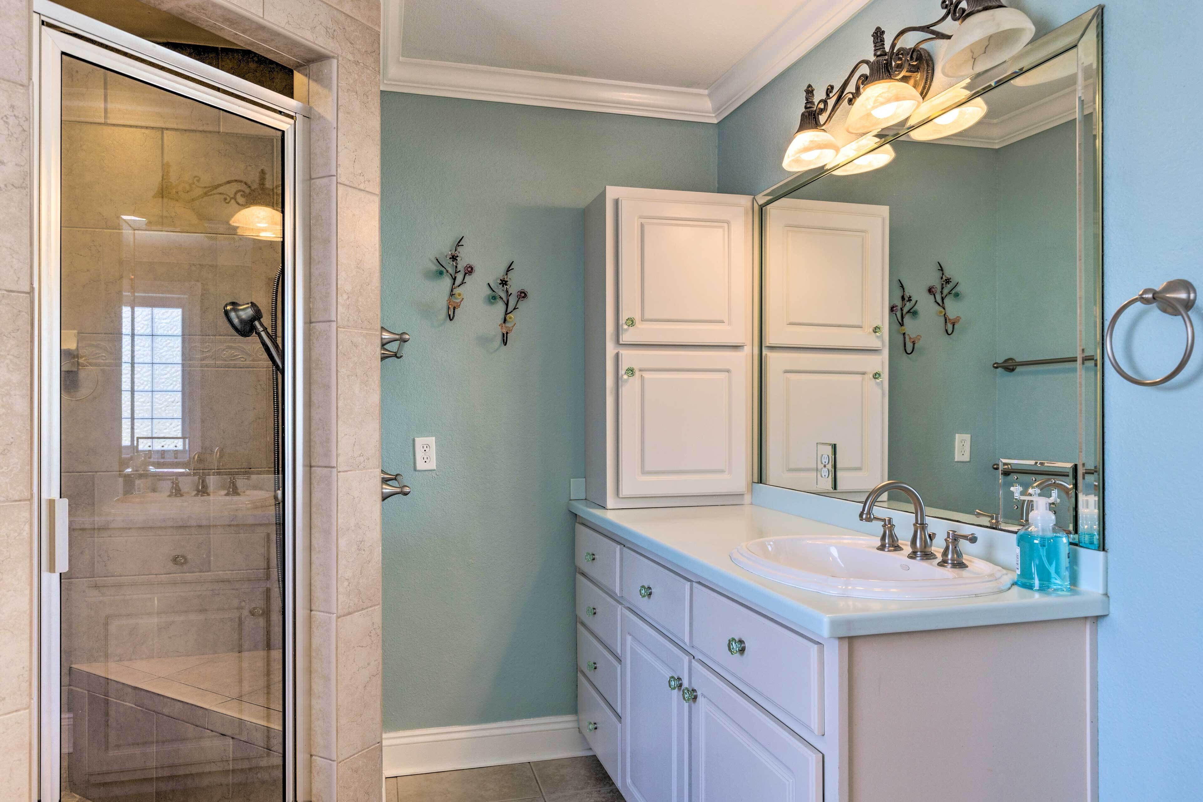 A bathroom with a glass-enclosed shower, a white vanity with a sink, and a large mirror.