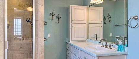 A bathroom with a glass-enclosed shower, a white vanity with a sink, and a large mirror.