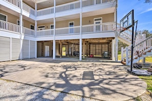 A multi-story building with a covered outdoor area, balconies, and a basketball hoop.