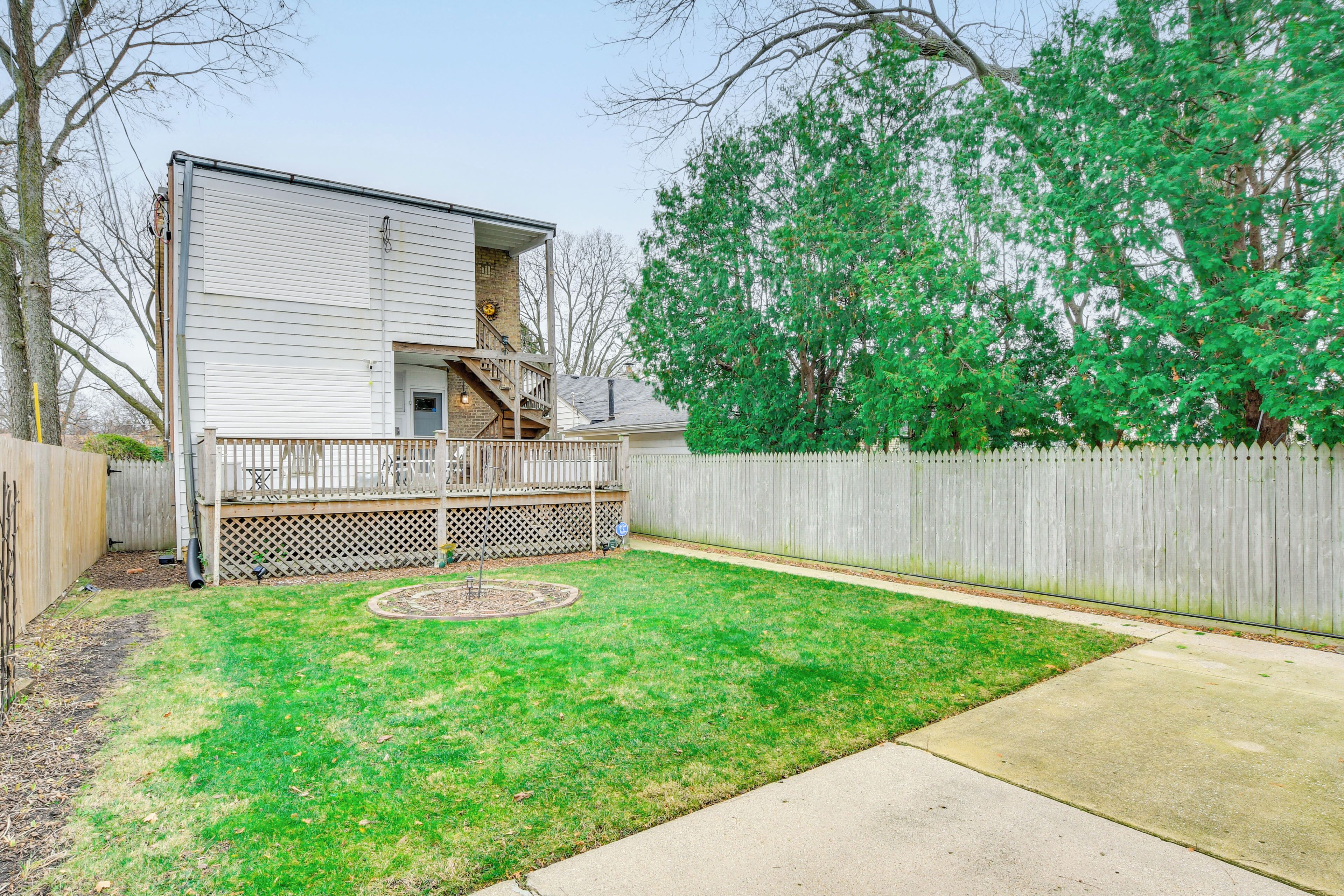 A two-story house with a deck and a fenced backyard.