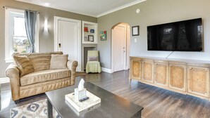 A living room with a beige sofa, a coffee table with a tissue box, a flat-screen TV mounted on the wall, and a wooden cabinet. - Pet-friendly Family Apartment - Near NU Campus! (Evanston)