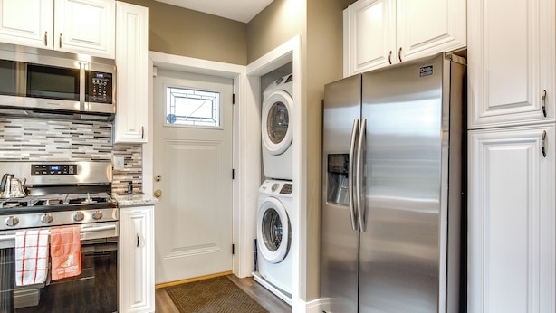 A kitchen with white cabinets, a stainless steel refrigerator, a microwave, an oven, and a washing machine. - Pet-friendly Family Apartment - Near NU Campus! (Evanston)