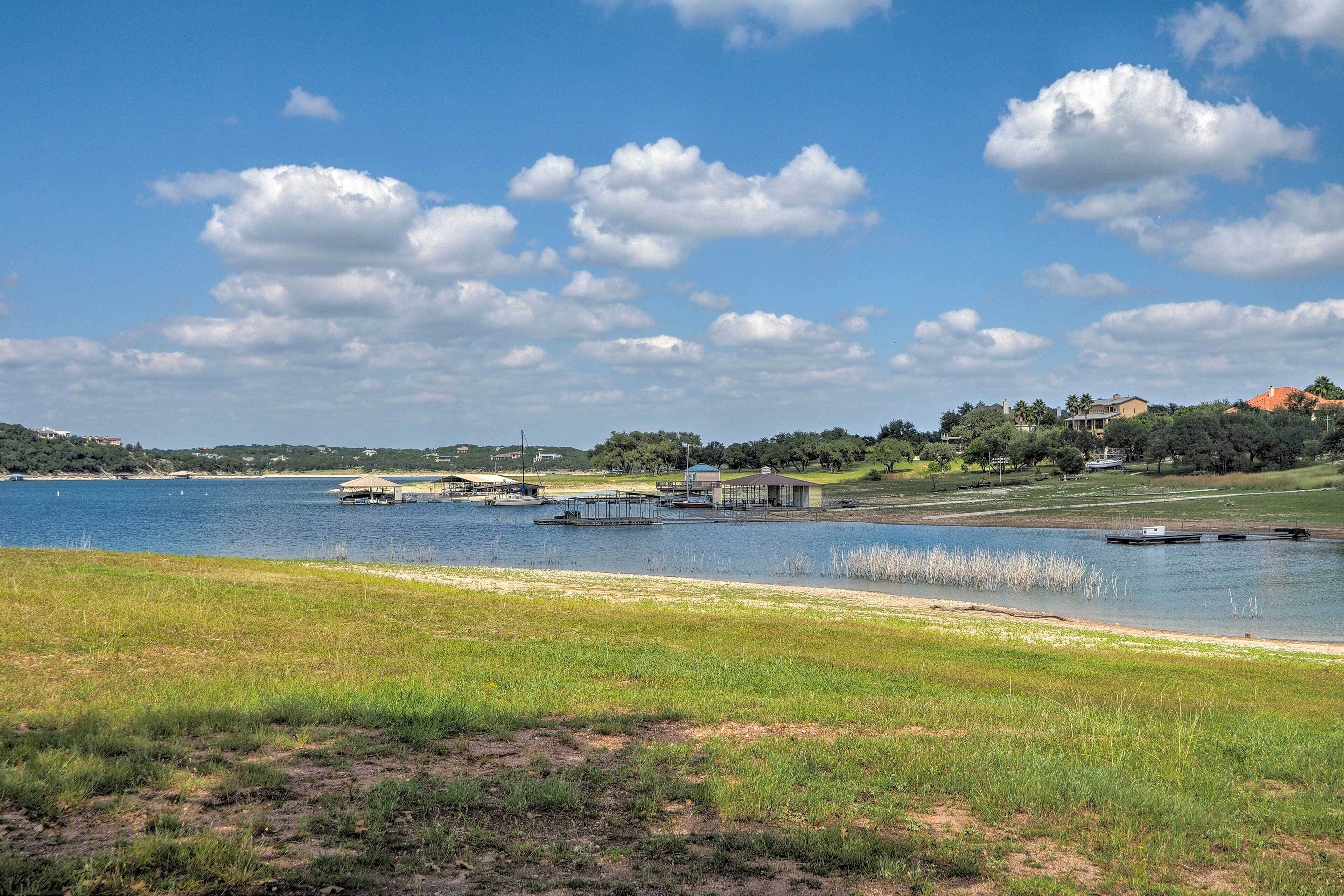 A lakeside view with boats, a grassy area, and buildings in the background.