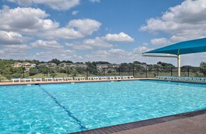 A swimming pool with clear blue water, surrounded by a fence, and a blue canopy overhead. - Waterfront Lake Travis Home w/ Pool Access! (Leander)