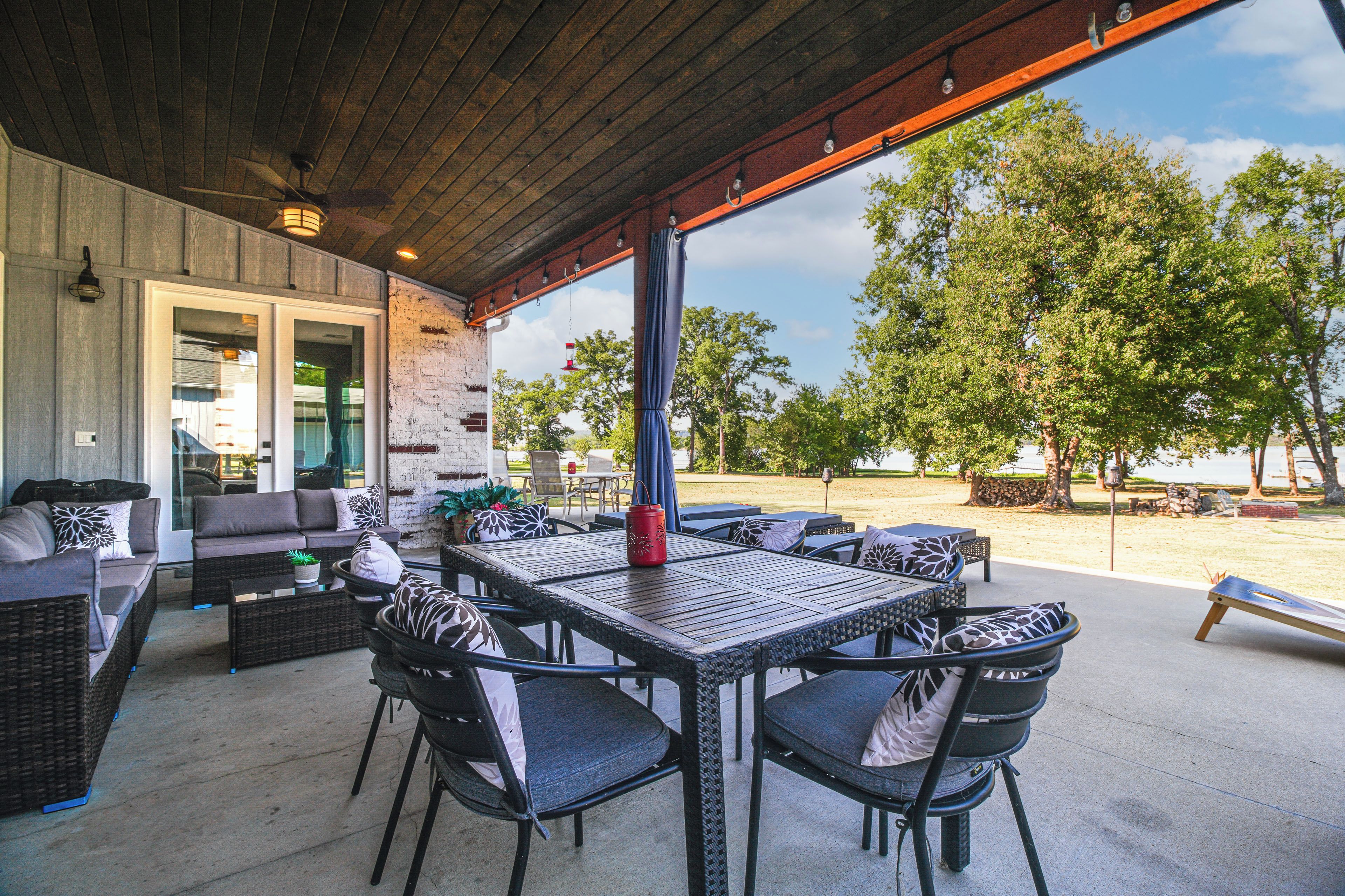 An outdoor patio with a covered seating area, a dining table, and chairs.