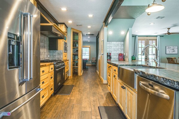 A modern kitchen with stainless steel appliances, wooden cabinets, and a large island with a sink.