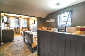 Un dormitorio con cama, mesita de noche y ventana con cortinas.