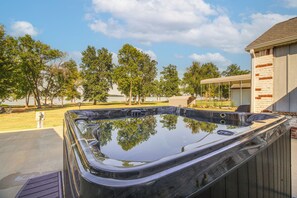 A hot tub in a backyard with trees and a building in the background.