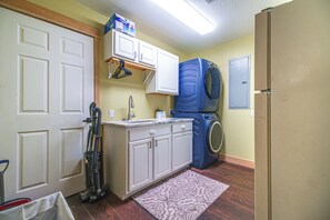 Une cuisine compacte équipée d’un lave-linge et d’un sèche-linge intégrés, d’un petit plan de travail et d’un aspirateur.