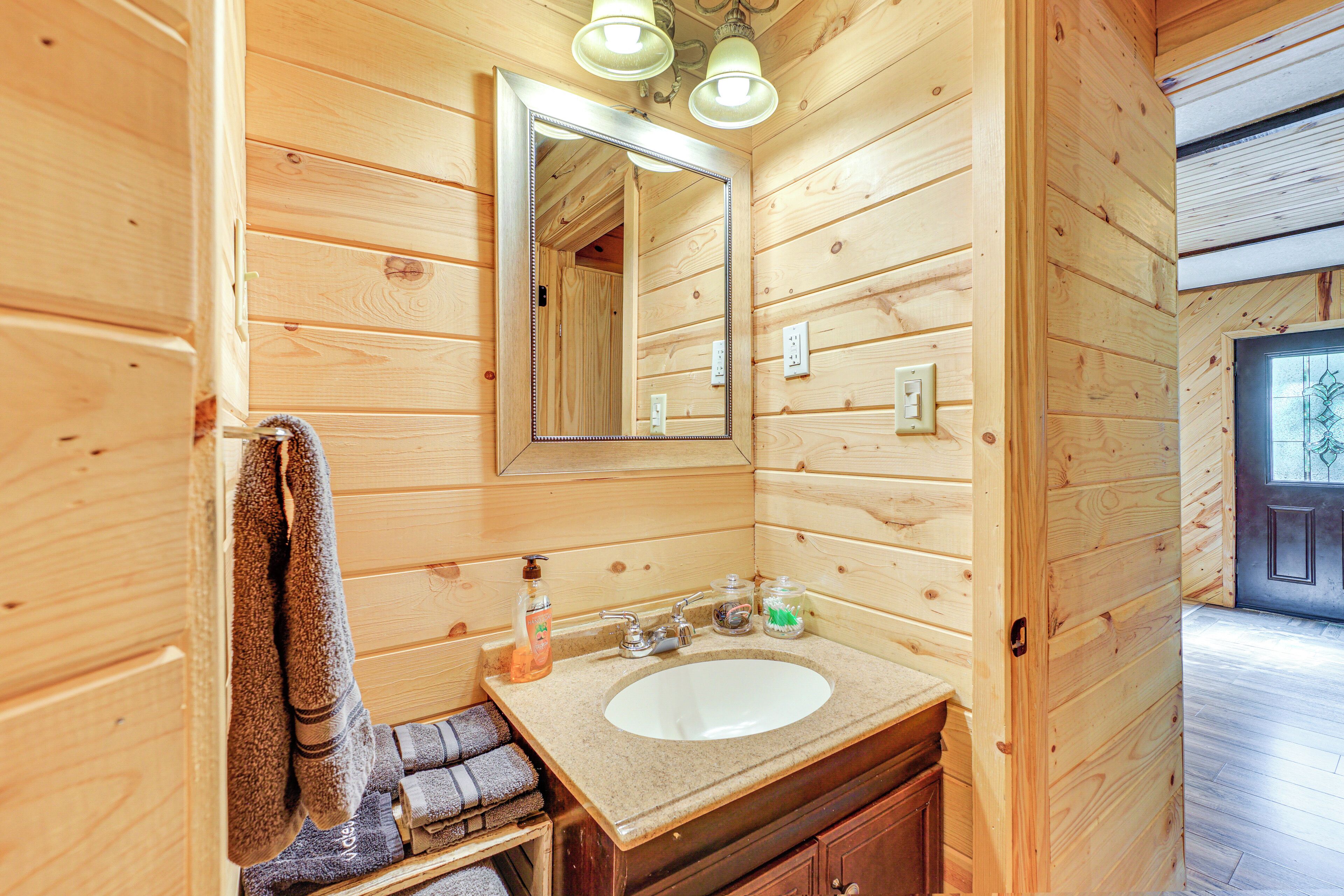 A wooden cabin bathroom with a sink, mirror, and towels.
