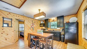Un intérieur en bois comprenant un coin cuisine, une table à manger avec des tabourets de bar et un réfrigérateur.