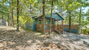 Une cabane dotée d’une terrasse en bois et de fondations en briques, entourée d’arbres.