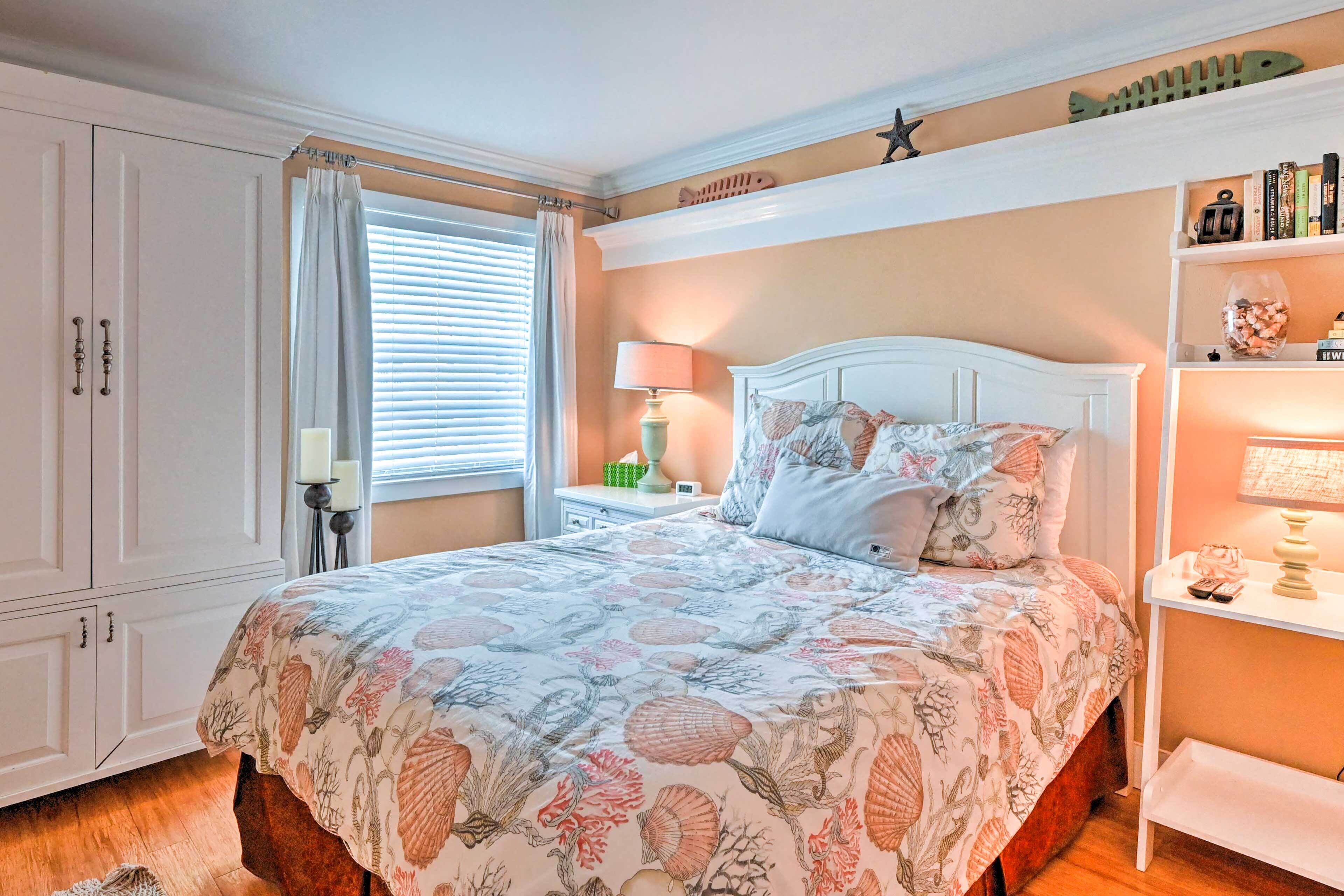 Une chambre à coucher avec un lit, des tables de chevet, une lampe, une étagère avec des livres et une fenêtre avec des rideaux.