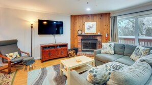 A cozy living room with a fireplace, a sofa, a TV, and a wooden cabinet.