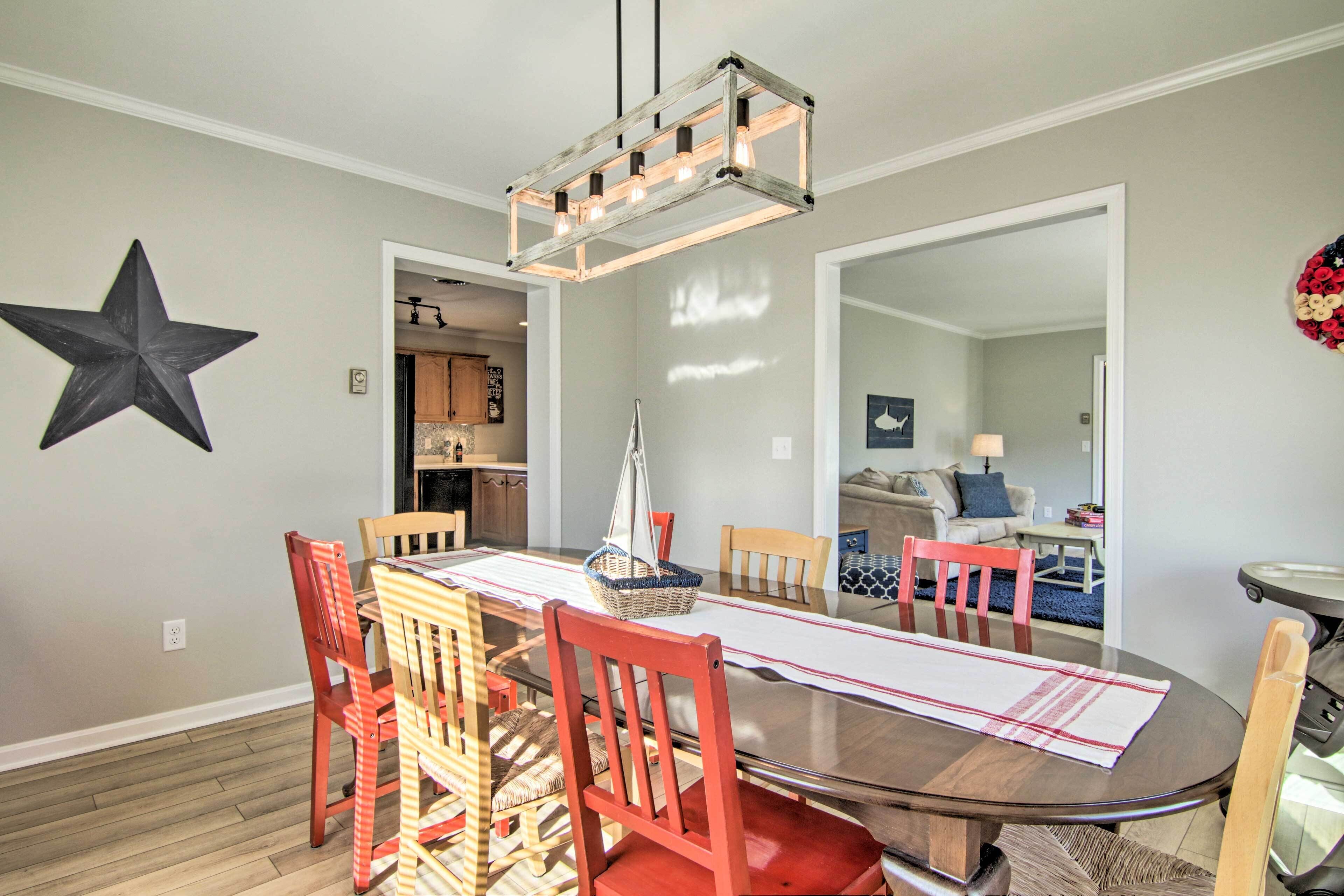 A dining area with a round table, red chairs, a wooden floor, and a star decoration on the wall.