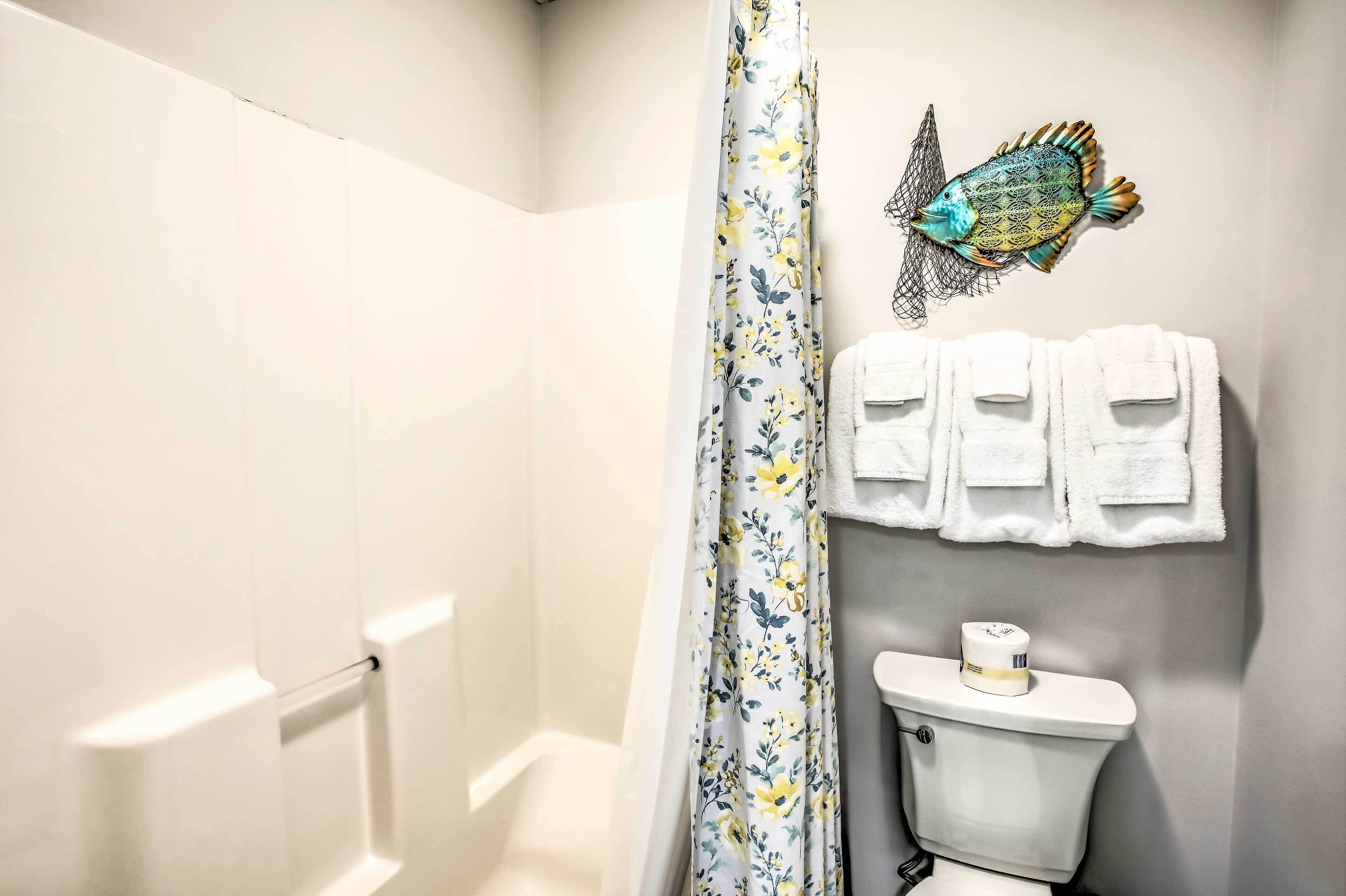 A bathroom with a shower curtain, a toilet, and a wall-mounted towel rack with towels.