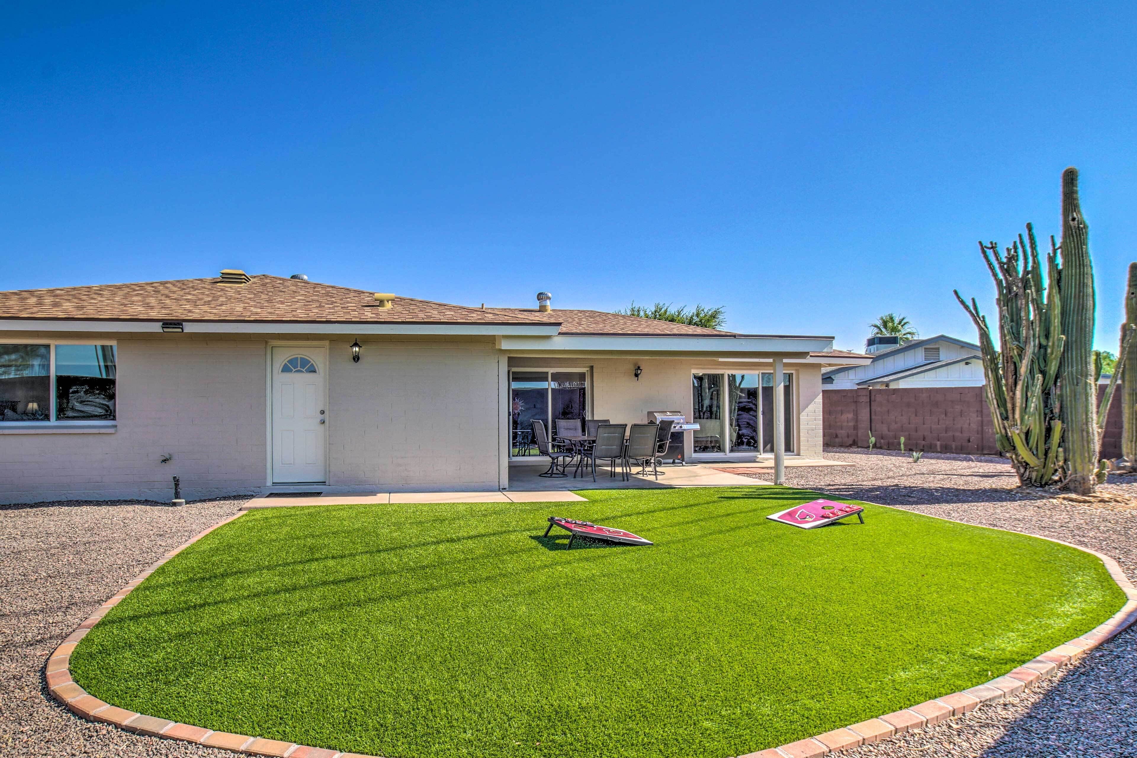 A house with a well-maintained lawn, a patio with outdoor furniture, and a cactus in the yard.