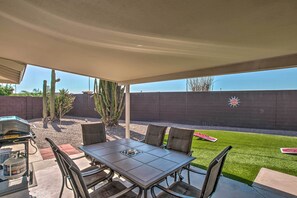 Une terrasse extérieure avec une table et des chaises, un barbecue et un cactus.