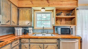 A kitchen with wooden cabinets, a stainless steel sink, a microwave, and a refrigerator.
