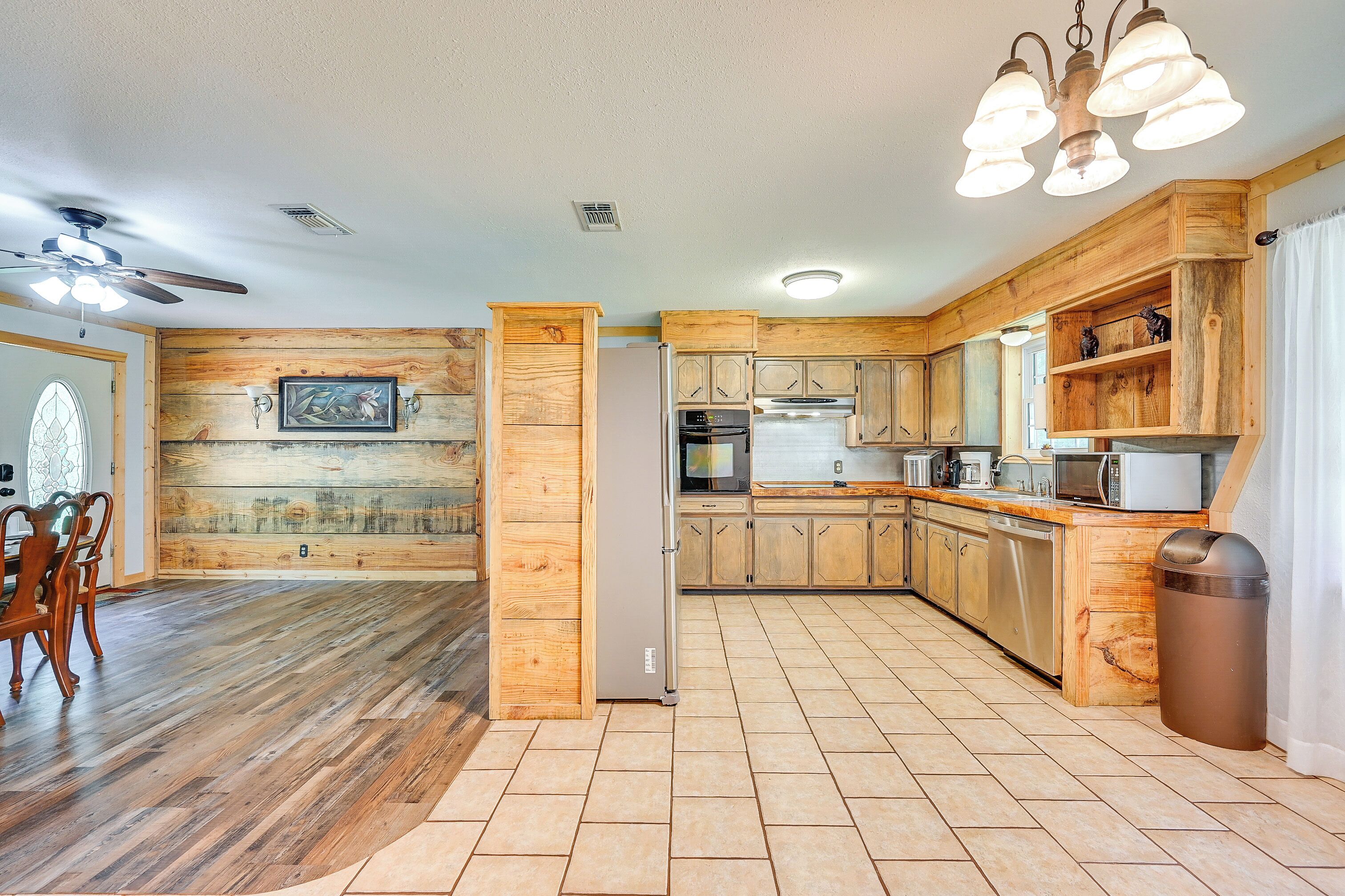 A spacious kitchen with wooden cabinets, a refrigerator, and a dining area with a chandelier.