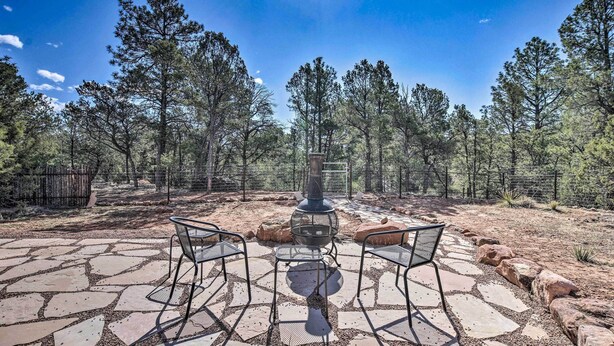 An outdoor patio with stone flooring, metal chairs, and a central fire pit. - Artist's Retreat w/ Pecos National Park Views! (Rowe)