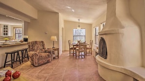 A spacious living room with a fireplace, a dining area, and a kitchen with a bar. - Artist's Retreat w/ Pecos National Park Views! (Rowe)