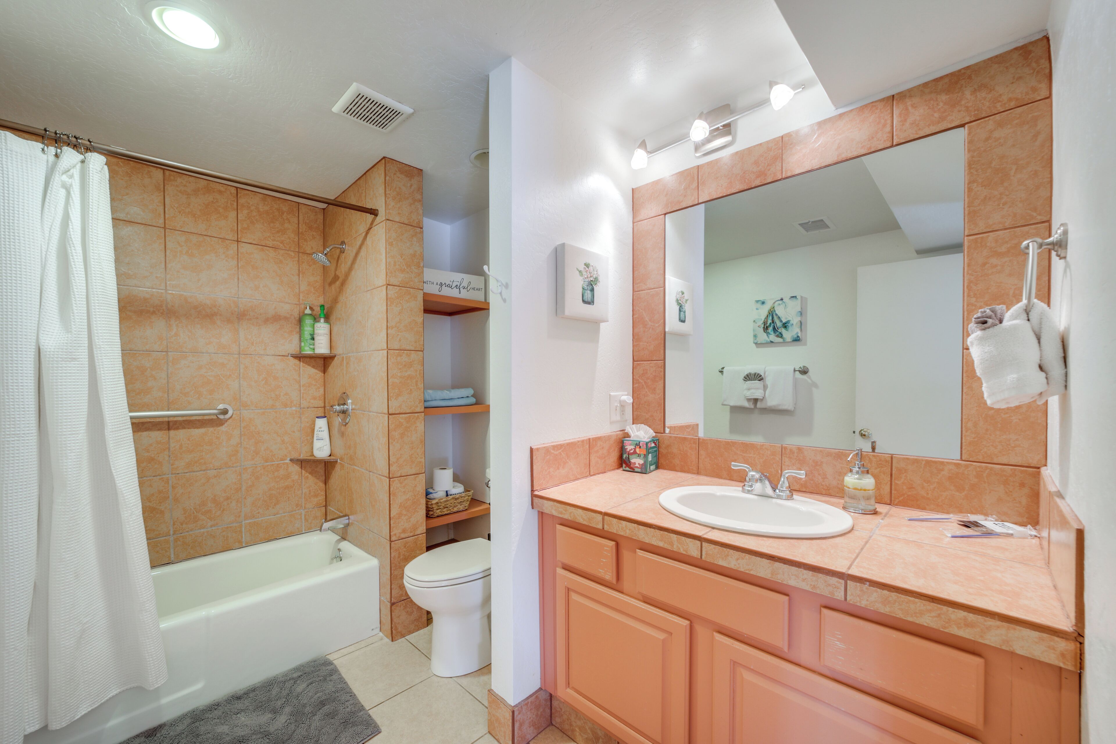 Een badkamer met bad, toilet, wastafel en een grote spiegel.