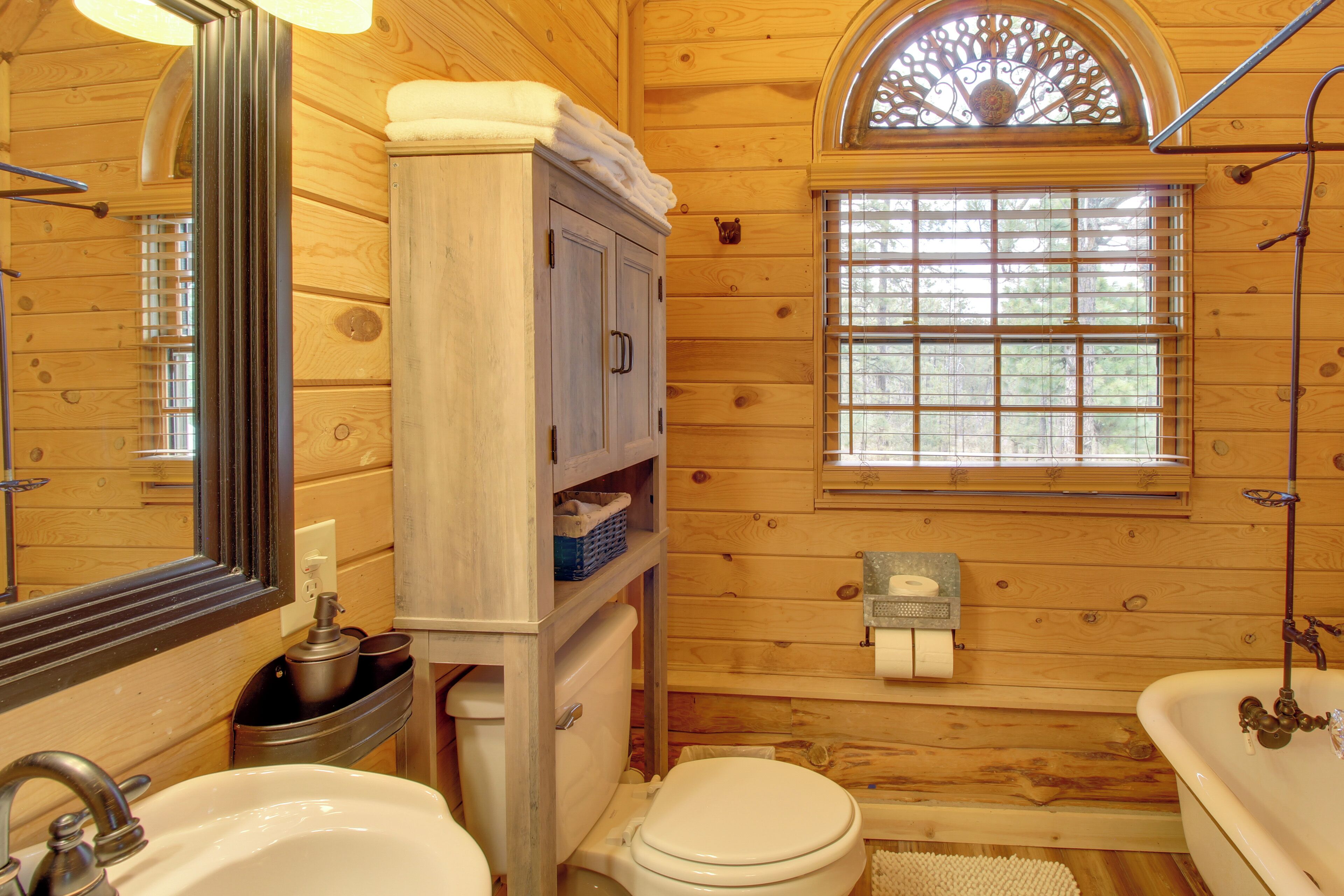 A wooden cabin bathroom with a sink, toilet, and bathtub.
