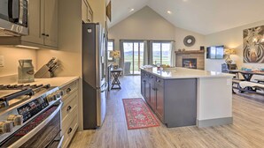 Een moderne keuken met roestvrijstalen apparatuur, een groot eiland en uitzicht op het omliggende landschap.